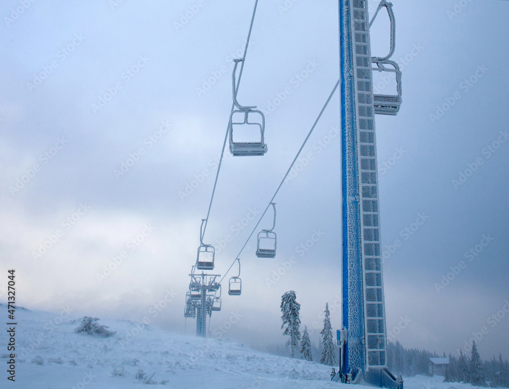 Frozen ski lift covered with frost on gloomy day in snowy mountains, path extending beyond the horizon Frozen ski lift covered with frost on gloomy day in snowy mountains, path extending beyond the horizon