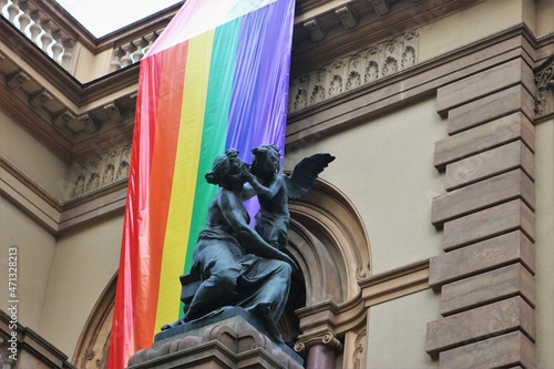 LGBT pride flag hanging from the Theatro Municipal de São Paulo behind a statue of a kissing angel photo