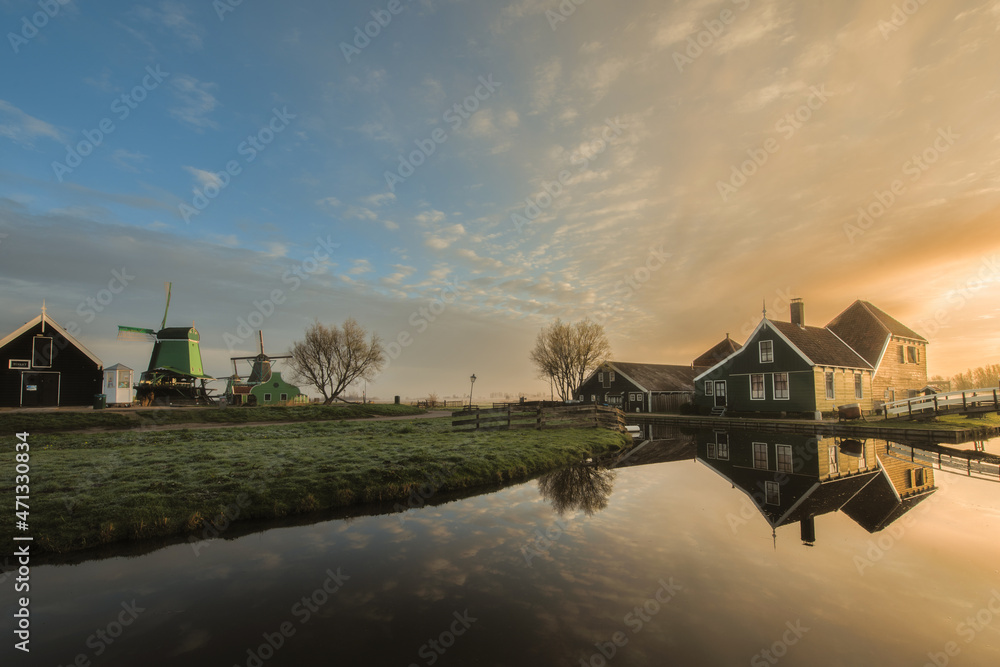 Obraz premium Traditional green dutch house with little wooden bridge against blue sky in the Zaanse Schans village.