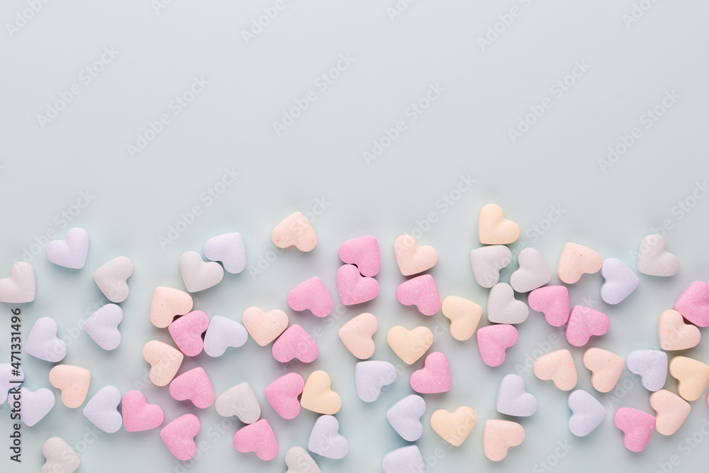 Composition with candy hearts on pastel blue background.