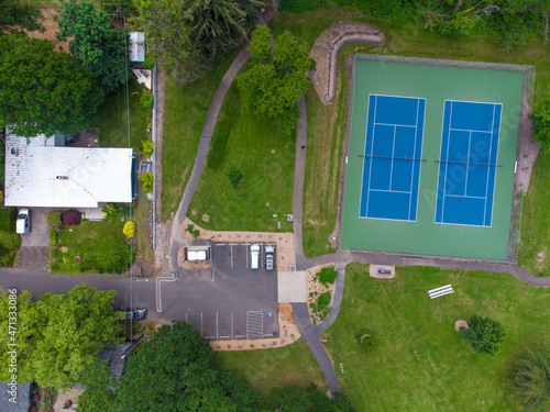 Aerial photograph. Small green city. Pedestrian paths, asphalt roads, car parking, sports ground. Lots of greenery. Abstraction. There are no people in the photo.