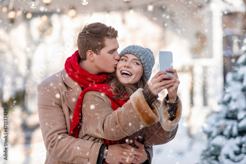 Cheerful couple enjoying first snow, taking selfie together