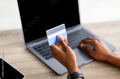 Cybershopping. Closeup view of black woman with credit card and laptop buying products on web, mockup for website