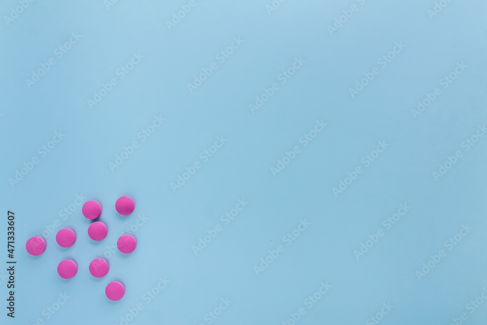 Pink tablets on a light blue background in the lower left corner, space for text.