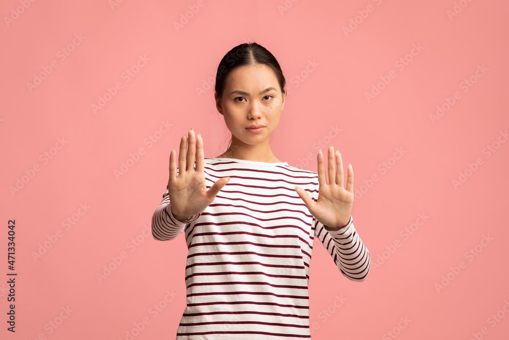 Portrait Of Serious Young Asian Female Showing Stop Gesture At Camera Portrait Of Serious Young Asian Female Showing Stop Gesture At Camera