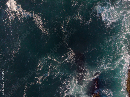 Aerial view. The seething watery abyss of dark turquoise color. White foam waves. Abstraction. Nature, ecology, geology, environmental protection. Background, wallpaper, texture.