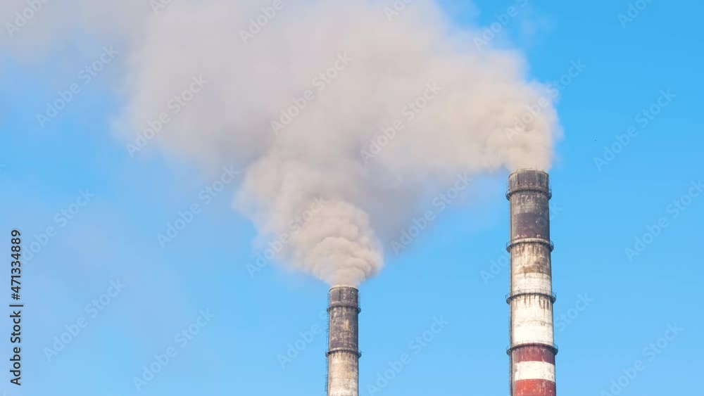 Closeup of thermal power plant high pipes with black smoke moving upwards polluting atmosphere. Production of electrical energy with fossil fuel concept Closeup of thermal power plant high pipes with black smoke moving upwards polluting atmosphere. Production of electrical energy with fossil fuel concept