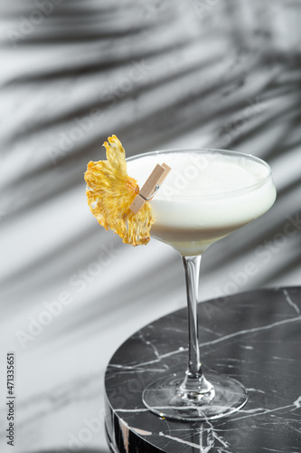 pina colada cocktail with shadow on jight backround. Pina Colada cocktail with decorations on marble table light background