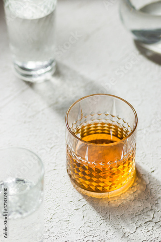 Whiskey in a glass among glasses with water white background 
