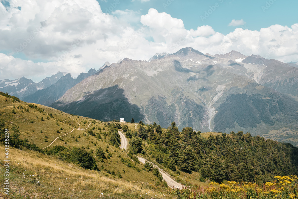 Fototapeta premium Summer mountain landscape near Mestia, Svaneti region, Georgia, Asia. Snowcapped mountains in the background. Blue sky with clouds above. Georgian travel destination