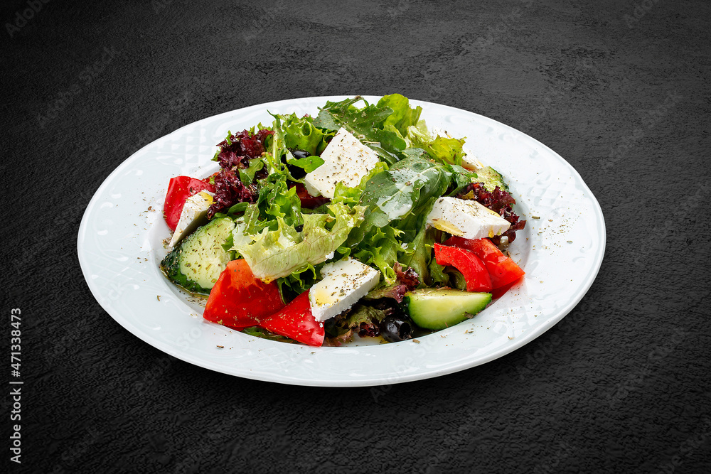 Greek salad with fresh vegetables and feta cheese. Isolated on a black background