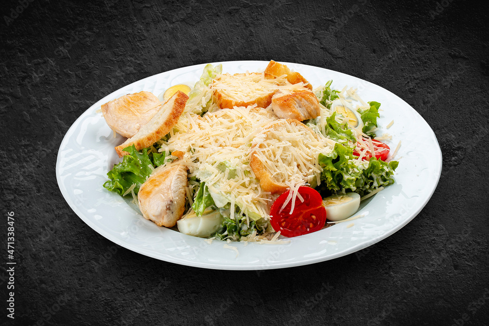 Caesar salad with chicken, egg and fresh vegetables. Isolated on a black background Caesar salad with chicken, egg and fresh vegetables. Isolated on a black background