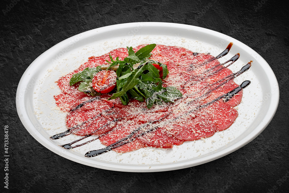 Veal carpaccio with parmesan cheese. Isolated on a black background Veal carpaccio with parmesan cheese. Isolated on a black background