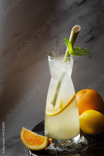 citrus lemonade with lemongrass and ingredients near on marble table. lemonade on jug with ice