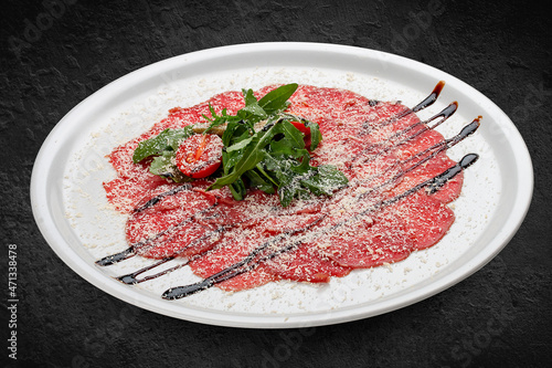 Veal carpaccio with parmesan cheese. Isolated on a black background