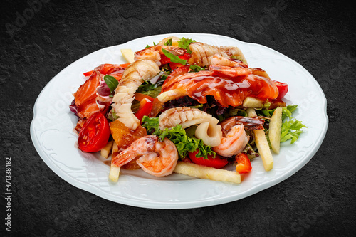 Salad Di Mare .Salad with shrimp, salmon and squid, orange and sweet pepper. Isolated on a black background