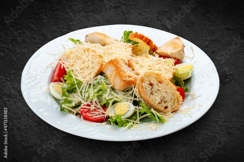 Caesar salad with chicken, egg and fresh vegetables. Isolated on a black background