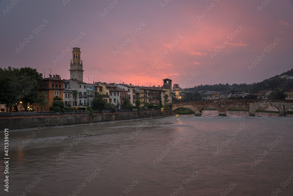 Buildings of the old town along the bank of the Adige river and the famous Stone Bridge (Ponte di Piettra) at sunset, Verona, Veneto Region, Italy