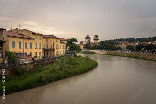 Colorful facades of the old town buildings by the Adige river with the parish of San Giorgio in Braida in the background on a cloudy day, Verona, Veneto Region, Italy © JMDuran Photography