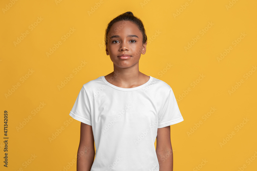 Serious calm teen afro american girl pupil in white t-shirt looking at camera alone Serious calm teen afro american girl pupil in white t-shirt looking at camera alone