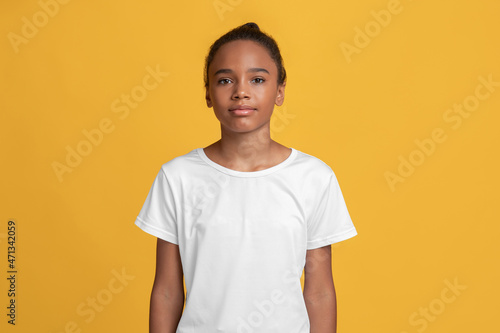 Serious calm teen afro american girl pupil in white t-shirt looking at camera alone photo