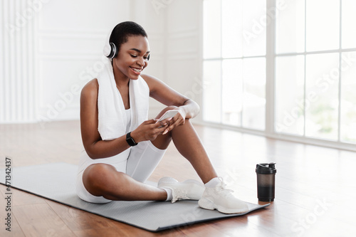 Fitness black lady listening to music using phone during break