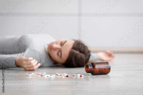 Obraz na plátně Sad european millennial lady unconscious lying on floor with scattered pills, co