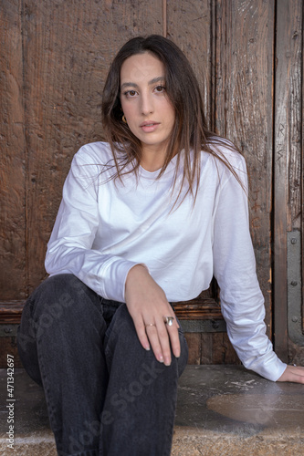 young woman sitting leaning against a wooden door