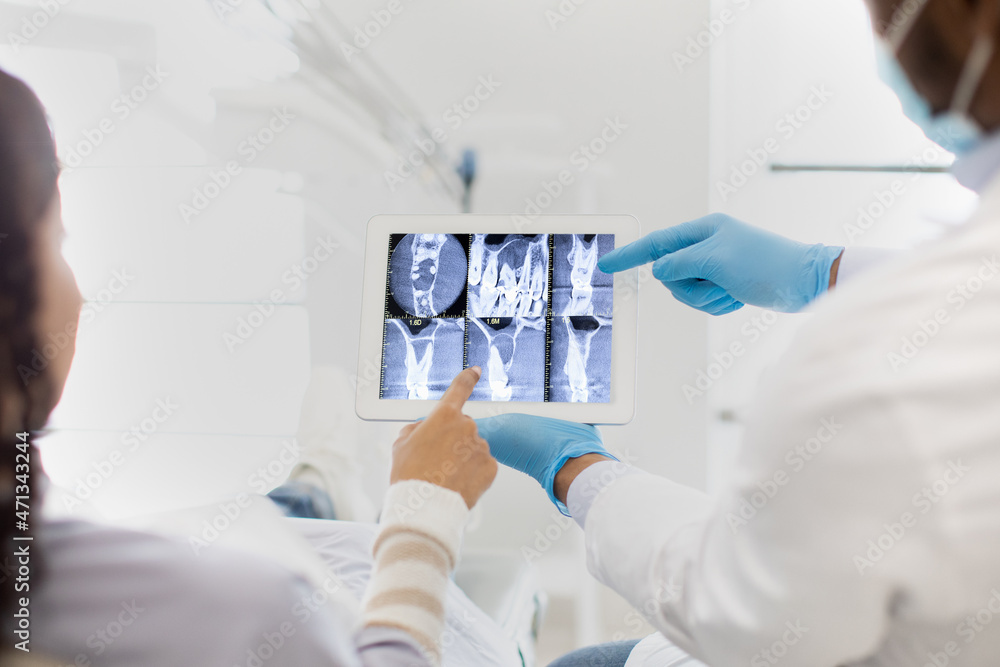 Dentist And Female Patient Looking At Teeth Xray Picture On Digital Tablet Dentist And Female Patient Looking At Teeth Xray Picture On Digital Tablet