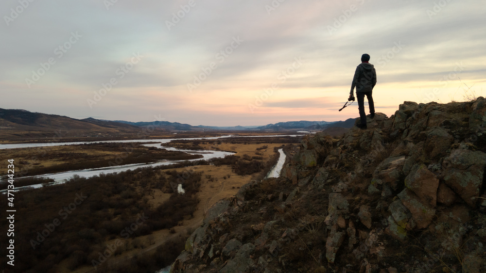 silhouette of a person with camera standing on a mountain top