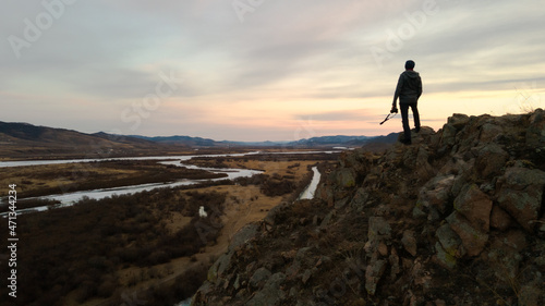 silhouette of a person with camera standing on a mountain top