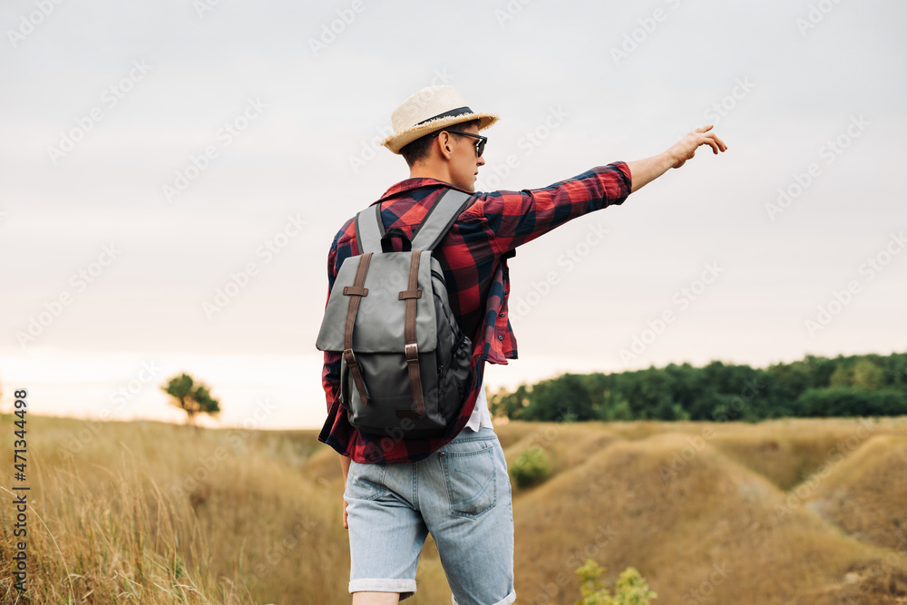 man with a backpack on a country walk on a summer day. Young people hiking in the countryside, outdoors at sunset man with a backpack on a country walk on a summer day. Young people hiking in the countryside, outdoors at sunset