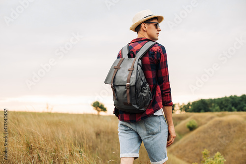 man with a backpack on a country walk on a summer day. Young people hiking in the countryside, outdoors at sunset © Shopping King Louie