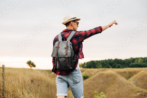 man with a backpack on a country walk on a summer day. Young people hiking in the countryside  outdoors at sunset
