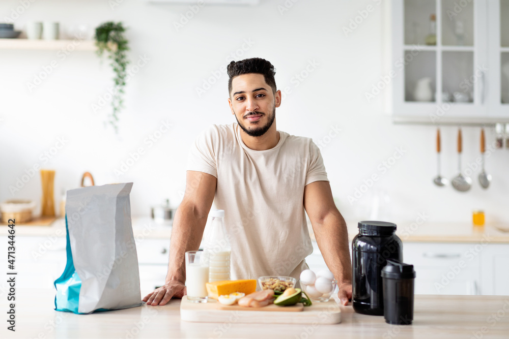 Portrait of handsome young Arab guy with healthy products and protein shake posing at kitchen Portrait of handsome young Arab guy with healthy products and protein shake posing at kitchen