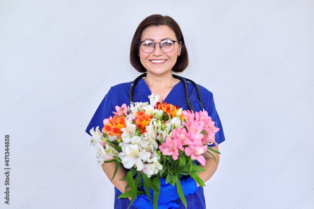 Woman doctor, nurse in blue with bouquet of flowers, on light background Woman doctor, nurse in blue with bouquet of flowers, on light background
