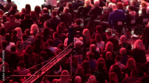 Production TV camera crane operate  in dark arena with crowd of people during business event meeting photo