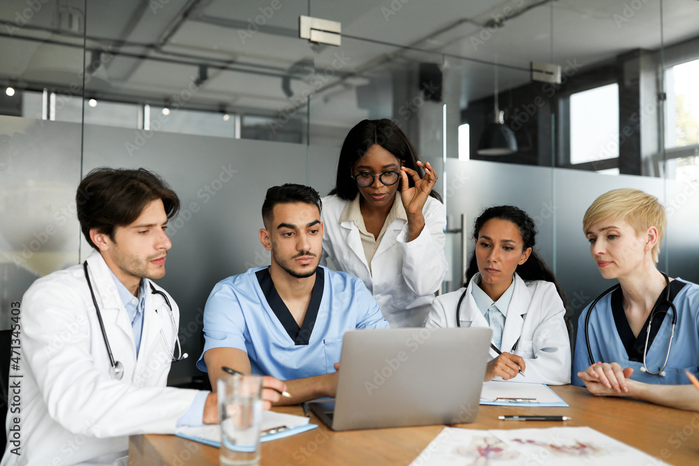 Professional team of doctors looking at notebook screen