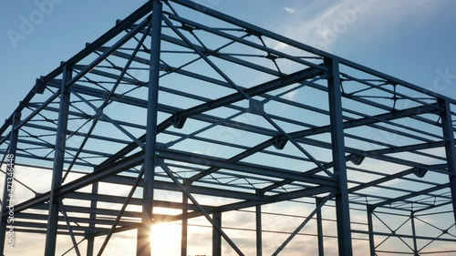 Metal construction - steel frame silhouette of unfinished industrial hall. Structure (framework) consisting of iron girders and beams meant to support the roof with sun shining through the grid.