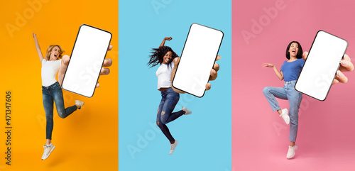 Happy glad excited international ladies jumping, fun, dancing and show phone with blank screen