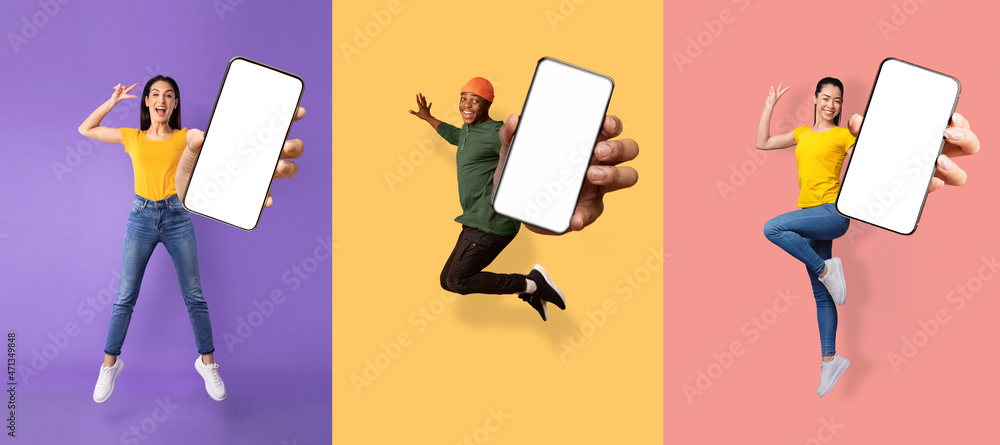 Obraz Glad excited young asian, european women and black guy jumping from joy and show phone fototapeta, plakat