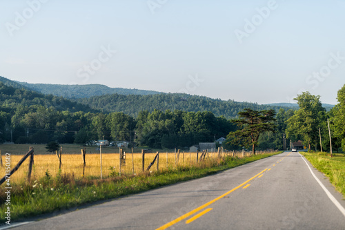 North Carolina highway road with blue sky Blue Ridge Mountains parkway with countryside rural scenery in Marion, McDowell County on US-221 and yellow farm fields, houses in summer