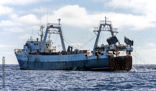 Large fishing trawler is fishing for fish and seafood in the ocean. photo