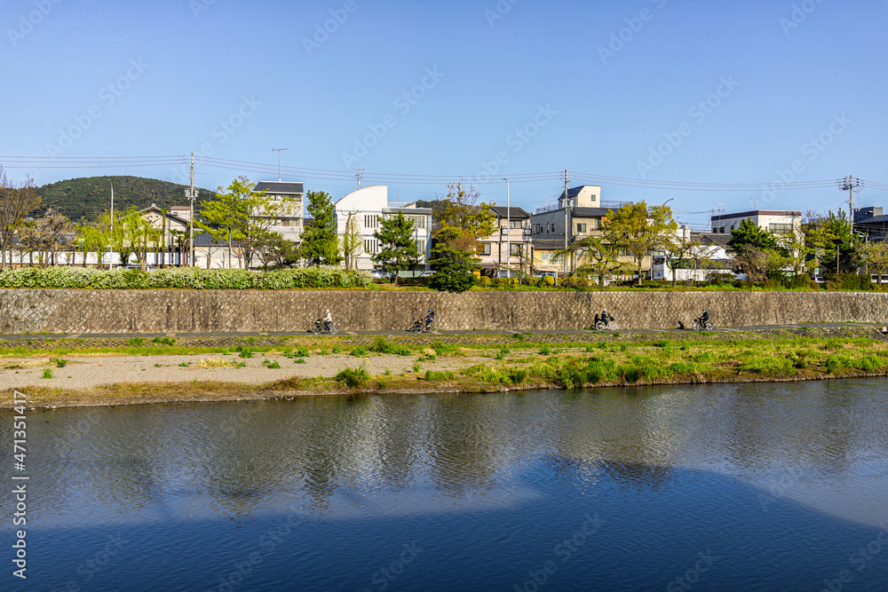 Kyoto, Japan Kamo river water in evening sunset with cityscape of buildings houses on bank of canal in spring springtime
