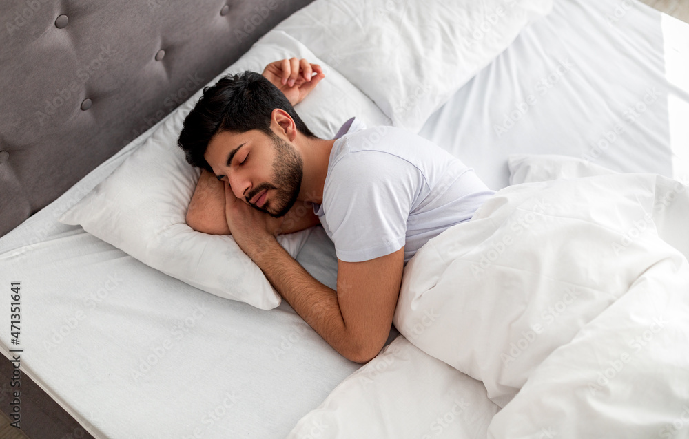Asleep young arab man sleeping, resting peacefully in comfortable bed, lying with closed eyes, free space Asleep young arab man sleeping, resting peacefully in comfortable bed, lying with closed eyes, free space