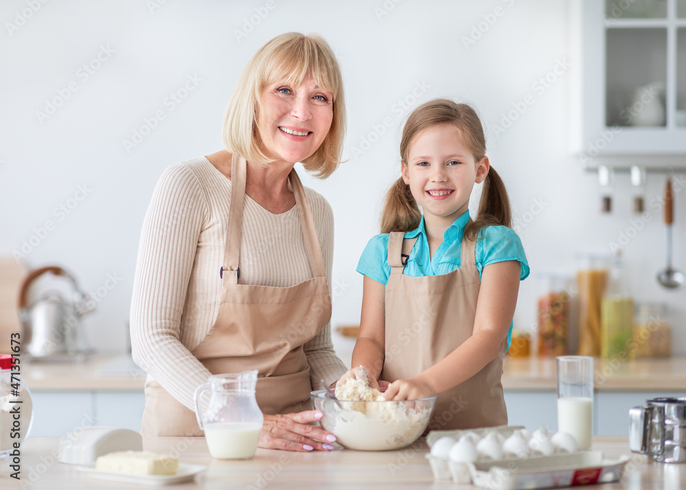 Happy nanny and her granddaughter kneading dough together Happy nanny and her granddaughter kneading dough together