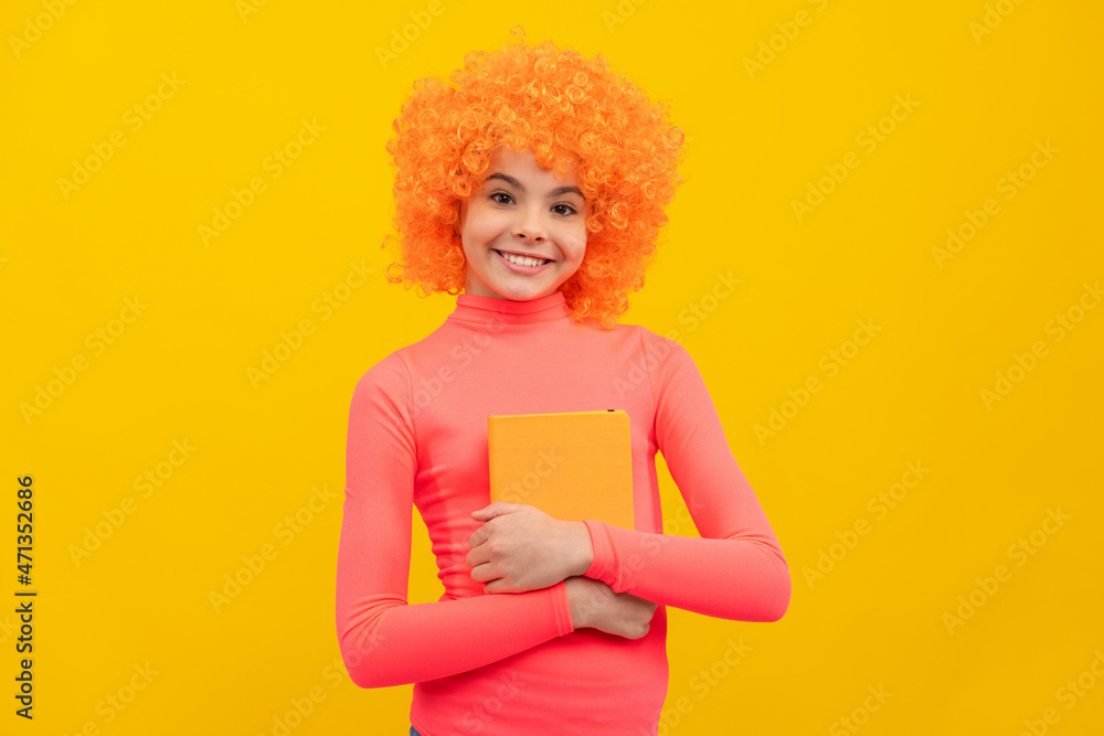 Happy girl child with orange hair in pink poloneck smile holding book yellow background, school