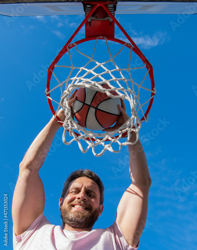 happy man player throw basketball ball through basket, winning