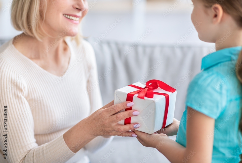 Little girl celebrating granny's day, greeting lady with wrapped box Little girl celebrating granny's day, greeting lady with wrapped box