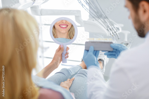Dentist applying sample from tooth scale to patient teeth reflection